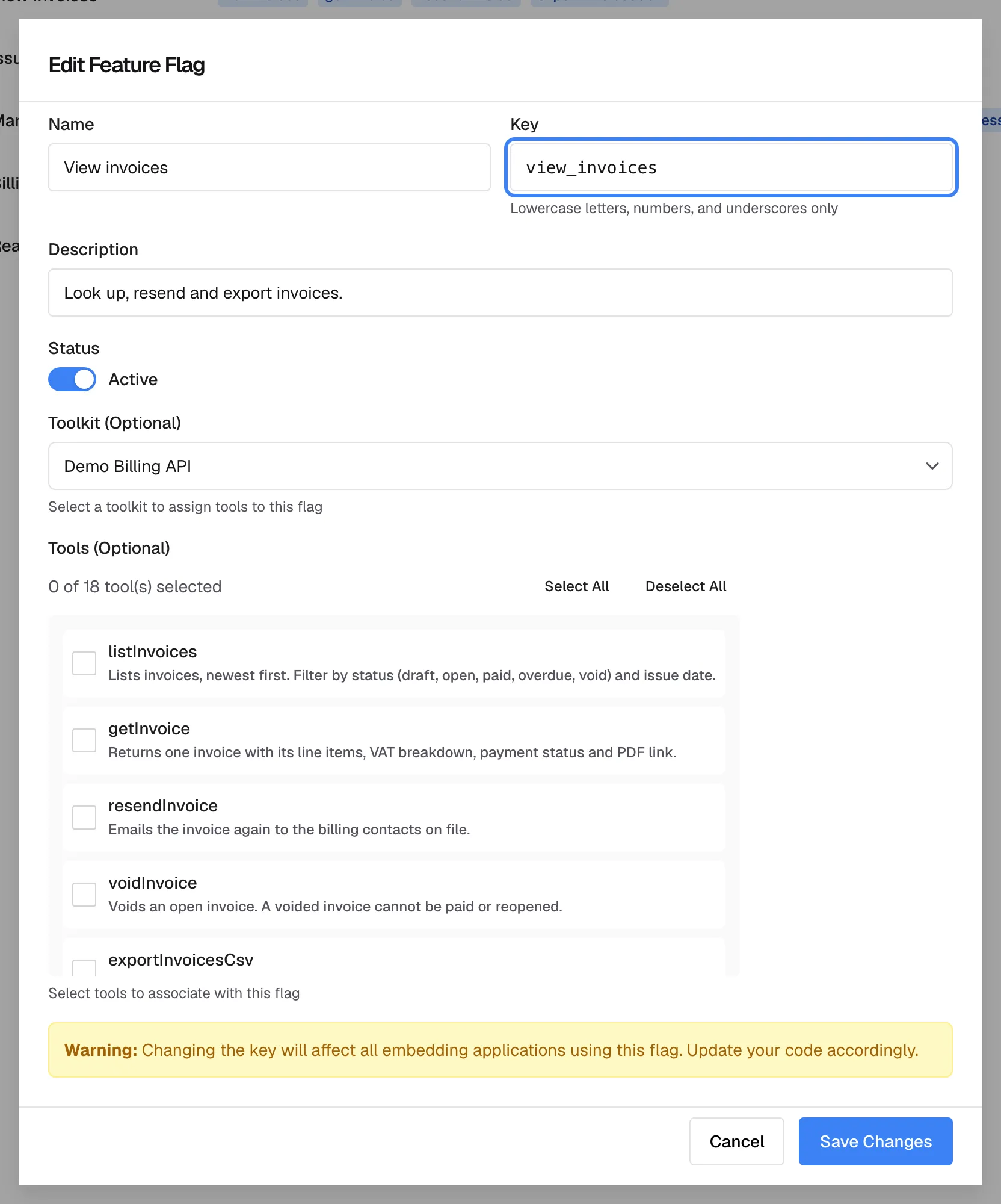 The "Edit Feature Flag" dialog for the policy "View invoices". The highlighted "Key" field shows view_invoices, the name the policy is known by. Below are "Description", the "Status" switch set to Active, "Toolkit (Optional)" with Demo Billing API and "Tools (Optional)", where the counter reads "0 of 18 tool(s) selected" and no box is ticked, although the list page shows four tools for this policy. A "Warning:" box says that changing the key affects every embedding application using it; "Cancel" and "Save Changes" sit at the bottom.